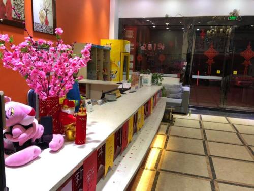 uma loja com um balcão com flores cor-de-rosa em 7Days Inn Bazhong International Trade City em Bazhong