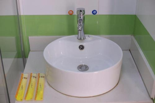 lavabo blanco con grifo en el baño en 7Days Inn Zhangjiakou Ming De North Road, en Zhangjiakou