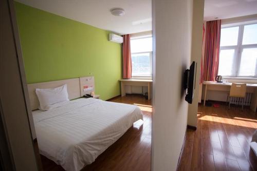1 dormitorio con cama blanca y paredes verdes en 7Days Inn Zhangjiakou Ming De North Road, en Zhangjiakou