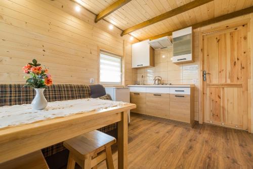 a kitchen with a table with a vase of flowers on it at Domki Pod Roztóczką in Hoczew