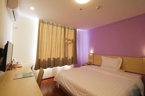 um quarto com uma cama branca e uma parede roxa em 7Days Inn ChengDu RenShou Shuyuan Road Haochi Street em Meishan