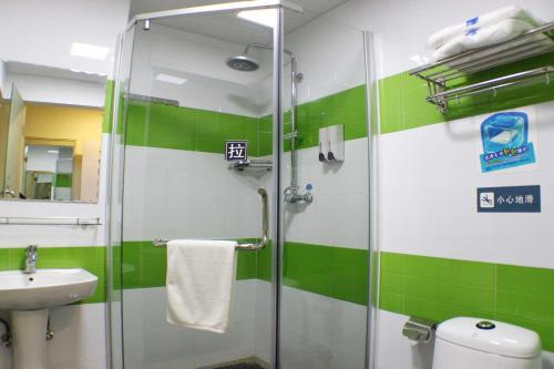 a green and white bathroom with a shower and a sink at 7Days Inn Shaoguan Renhua Mount Danxia in Shaoguan
