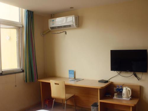 Zimmer mit einem Schreibtisch, einem TV und einem Computer. in der Unterkunft 7Days Inn Shangqiu democratic road WAL-MART in Shangqiu