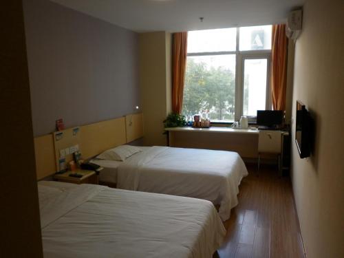 um quarto de hotel com duas camas e uma janela em 7Days Inn Tianjin Development Zone The Fifth Avenue Convention and Exhibition Center em Binhai