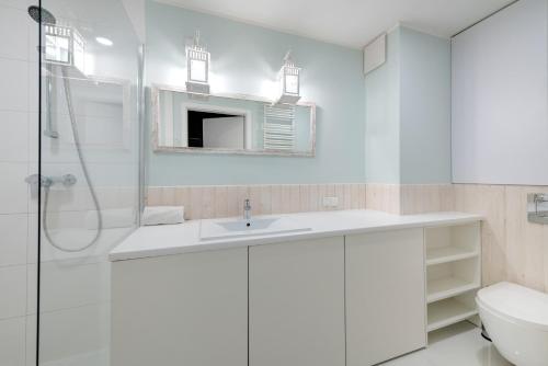 a white bathroom with a sink and a toilet at 3 City Apartments - Admiralski in Gdańsk
