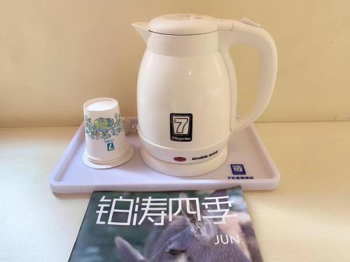 a tea kettle on a tray next to a magazine at 7Days Inn Shijiazhuang Friendship Avenue Jianguo Road in Shijiazhuang