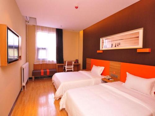 una camera d'albergo con due letti e una televisione di 7Days Premium Ji`nan Luokou Clothing City Wuying Hill North Road a Jinan