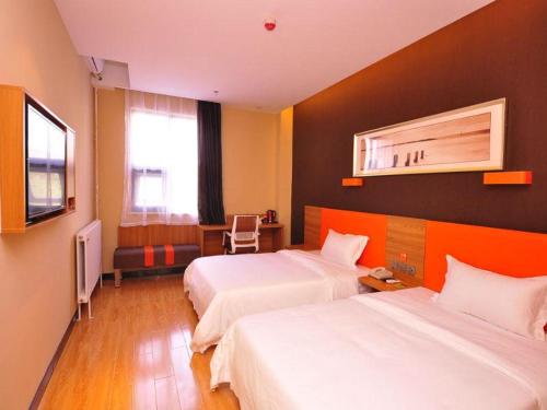 a hotel room with two beds and a television at 7Days Premium Ji`nan Luokou Clothing City Wuying Hill North Road in Jinan