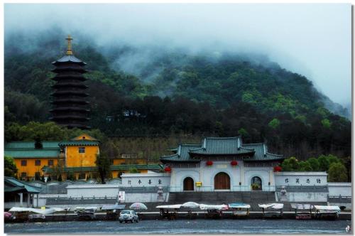 a building with a pagoda in front of a mountain at 7Days Inn Shaoguan Lechang Darunfa in Shaoguan