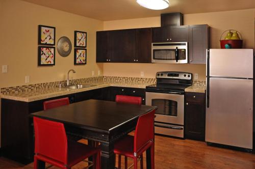 a kitchen with a black table and a white refrigerator at Oxford Suites Portland - Jantzen Beach in Portland