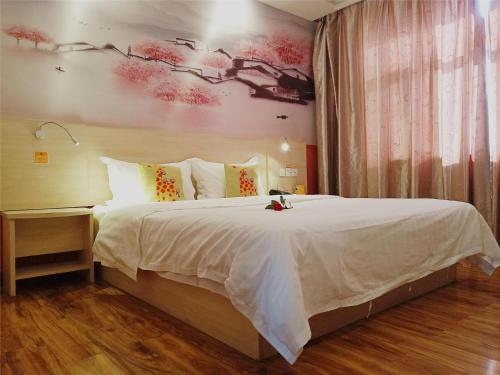 - une chambre avec un grand lit blanc orné d'une peinture murale dans l'établissement 7Days Inn Linhe Railway Station, à Bayannuur