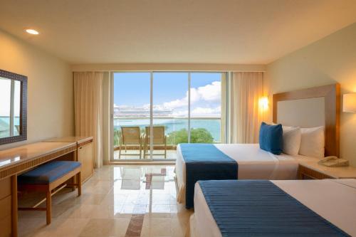 um quarto de hotel com duas camas e vista para o oceano em Grand Park Royal Cozumel - All Inclusive em Cozumel