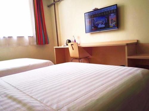 a bedroom with two beds and a tv on the wall at 7Days Inn Weinan Jiefang Road railway station in Weinan