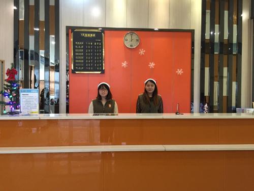 dos mujeres están de pie en un mostrador en una tienda en 7Days Inn Chongqing Penghu Pengshui Garden, en Pengshui
