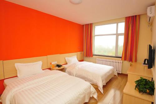 1 dormitorio con 2 camas y pared de color naranja en 7Days Inn Dezhou Qihe Coach Terminal, en Huadian