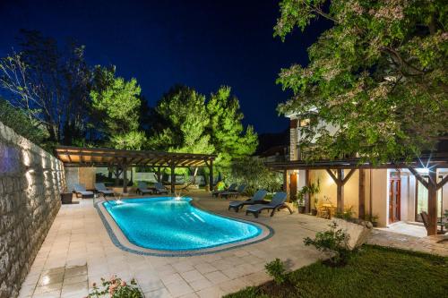 a swimming pool in a backyard at night at Palazzo Banicevic Luxury Rooms in Kotor