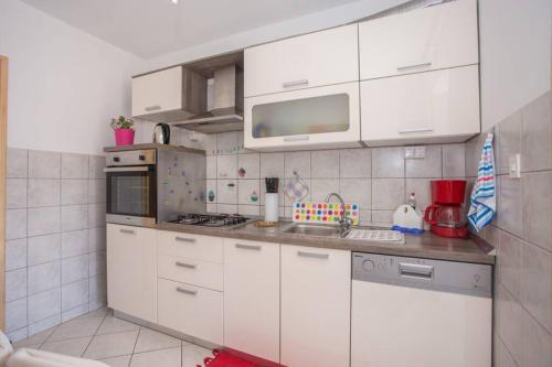 a kitchen with white cabinets and a sink and a microwave at Apartment Nebo in Poreč