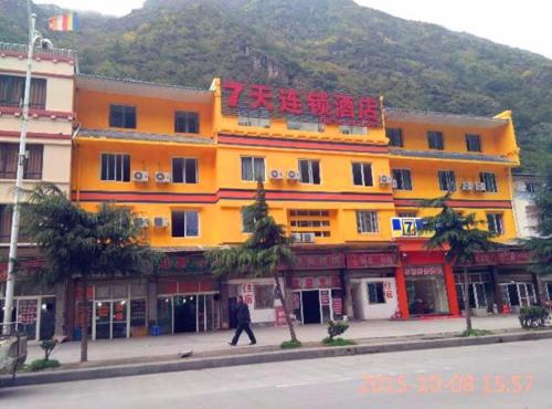a man walking in front of a yellow building at 7Days Inn Kangding passenger terminal station in Garze