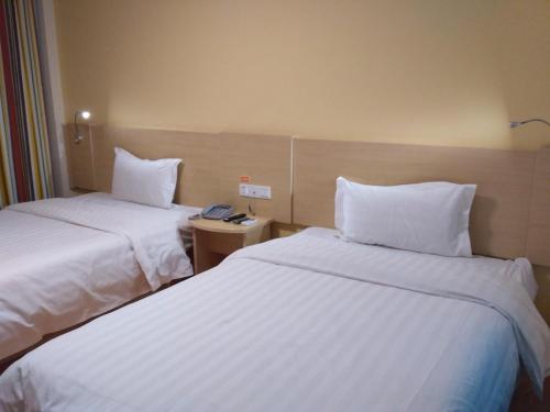 a hotel room with two beds with white sheets at 7Days Inn Kangding passenger terminal station in Garze