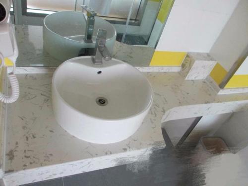 a white sink in a bathroom with a mirror at 7Days Inn Dongsheng Railway Station in Zhaoyoufang