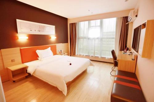 una camera da letto con un grande letto bianco e una finestra di 7Days Premium Weihai High-speed Rail Station Bathing Beach a Weihai