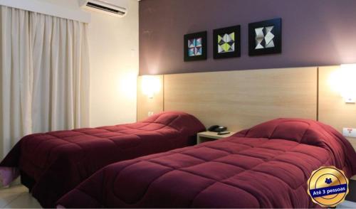 two beds in a hotel room with red covers at The World Indaiatuba in Indaiatuba