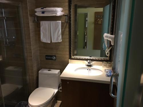 Hegang的住宿－7天酒店·鹤岗金广大厦店，一间带卫生间、水槽和镜子的浴室