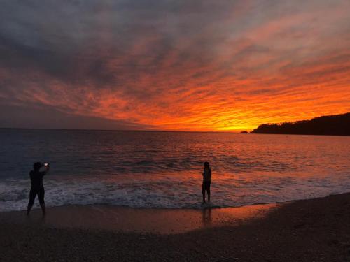 two people standing on the beach at sunset at Mimoza Hotel in Oludeniz