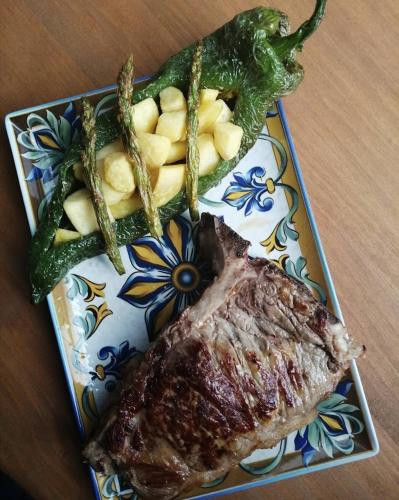 a plate of food with a piece of meat and vegetables at Hospedium Hotel El Nido de Alcudia Suites in Almodóvar del Campo
