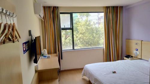 a hotel room with a bed and a window at 7Days Inn Yiyang victory road in Shangrao