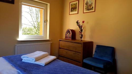 a bedroom with a bed and a chair and a window at Apartament Lawenda in Łeba
