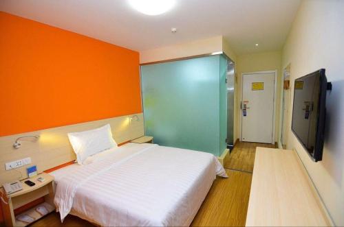 ein Schlafzimmer mit einem weißen Bett und einer orangefarbenen Wand in der Unterkunft 7Days Inn Kaifeng Qingming Shangheyuan Daliangmen in Kaifeng