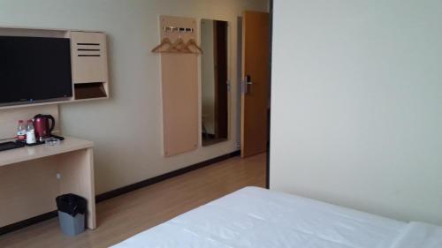um quarto com uma cama, uma televisão e uma porta em 7Days Premium Ziyang Anyue Ningdu Avenue em Yueyang