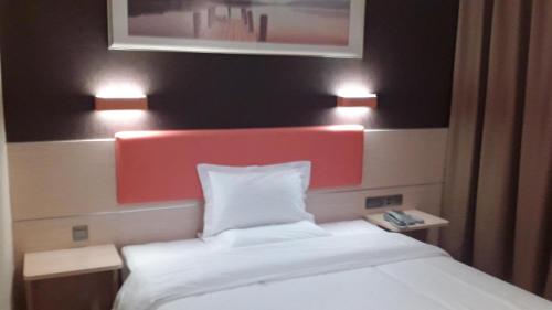 um quarto com uma cama branca com duas luzes em 7Days Premium Ziyang Anyue Ningdu Avenue em Yueyang