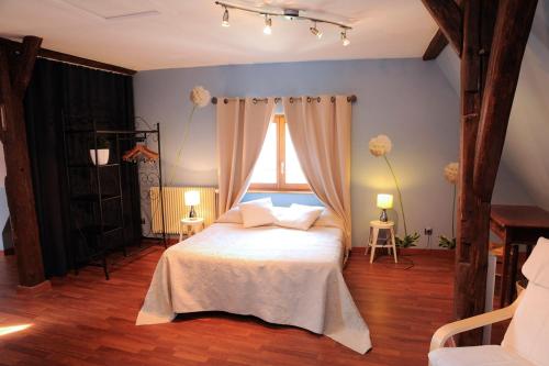 Schlafzimmer mit einem weißen Bett und einem Fenster in der Unterkunft La Maison Bleue in Kientzheim