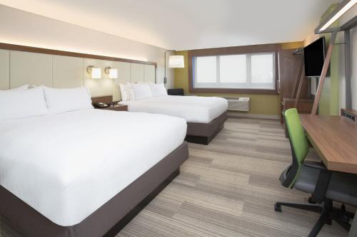 ein Hotelzimmer mit 2 Betten und einem Schreibtisch in der Unterkunft Holiday Inn Express & Suites - Dayton Southwest, an IHG Hotel in Dayton