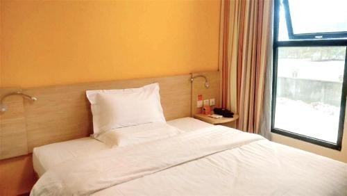 sypialnia z łóżkiem z białą pościelą i oknem w obiekcie 7Days Inn Langzhong Seven Mile Avenue w mieście Langzhong