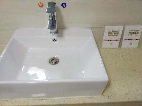 a white sink with a faucet on a counter at 7Days Inn Aksu Airport in Wen-su-lao-ch'eng
