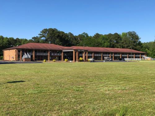 a large building with a grass field in front of it at American Inn Chesapeake - Portsmouth in Chesapeake