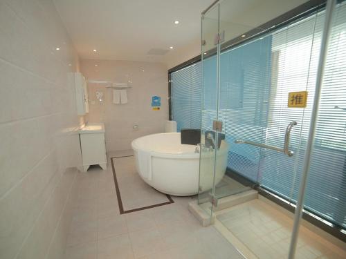 een badkamer met een bad en een glazen douche bij 7Days Inn Suzhou Industrial Park Sheng Pu Tongjiang Road in Suzhou