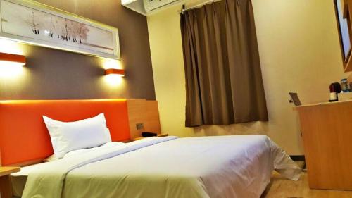 a bedroom with a large white bed with an orange headboard at 7Days Premium Chongqing Fuling Riverside Avenue in Fuling
