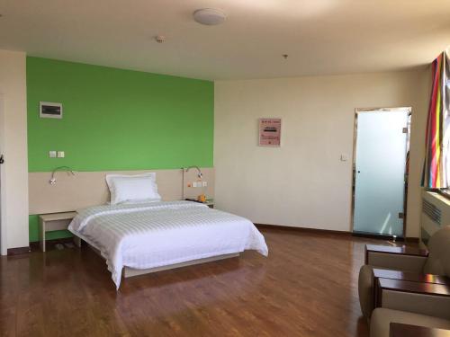 - une chambre avec un lit et un mur vert dans l'établissement 7Days Inn Chifeng Linxi Haichuan Square Branch, à Linxi