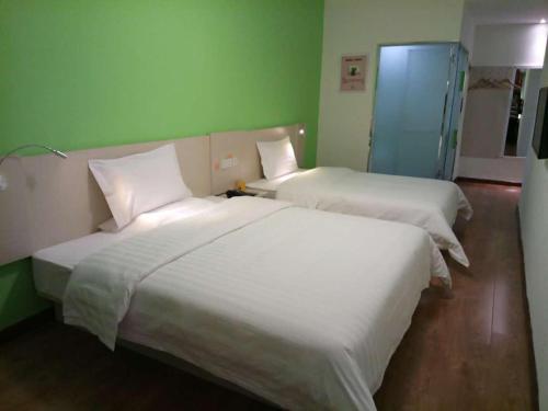 two beds in a room with green walls at 7Days Inn Chifeng Linxi Haichuan Square Branch in Linxi