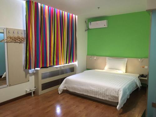 1 dormitorio con 1 cama y una ventana colorida en 7Days Inn Chifeng Linxi Haichuan Square Branch, en Linxi