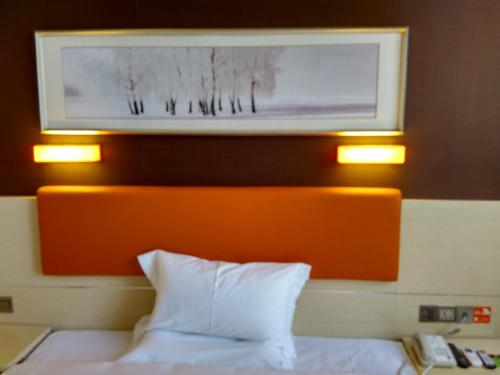 un letto con testiera arancione e due luci sopra di esso di 7Days Premium Shaoguan Shixing Road a Nanxiong