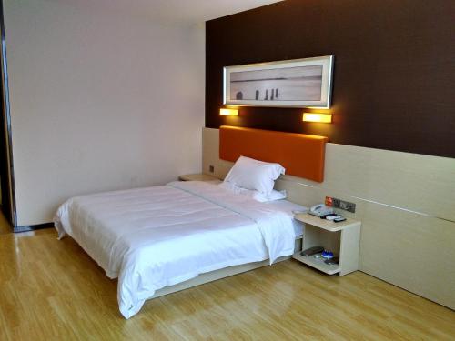 una camera d'albergo con letto e TV a parete di 7Days Premium Shaoguan Shixing Road a Nanxiong