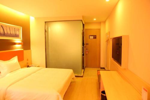 a hotel room with a bed and a sliding glass door at 7Days Premium Shihezi Recreation Plaza Merino Museum in Shihezi