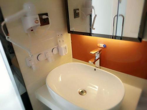 a bathroom with a white sink and a mirror at 7Days Premium Shizuishan Dawukou in Shizuishan