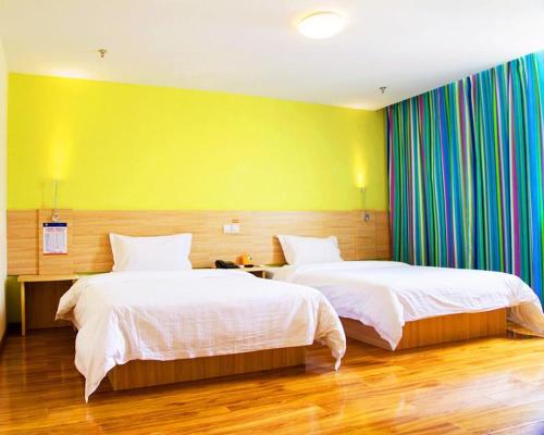 1 dormitorio con 2 camas y pared amarilla en 7Days Inn Chongqing Yunyang passenger terminal station, en Shuangjiang