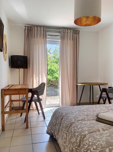 a bedroom with a bed and a desk and a window at Studio en face Hopital Nord avec terrasse in Saint-Priest-en-Jarez
